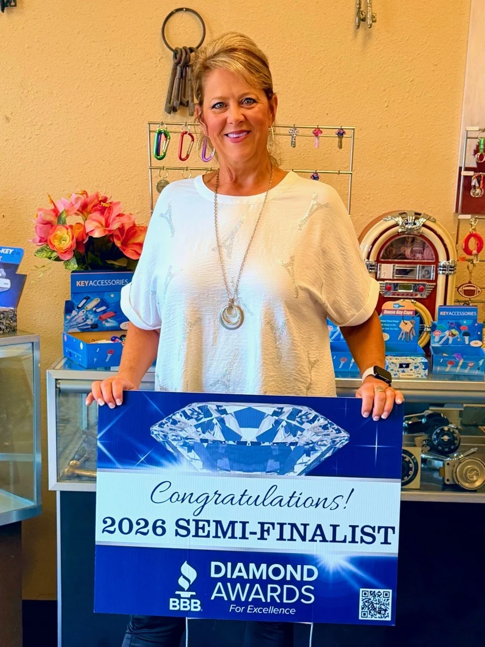 A woman at Noack Locksmith holds the unaltered sign reading 2026 Semi-Finalist, BBB Diamond Awards for Excellence.